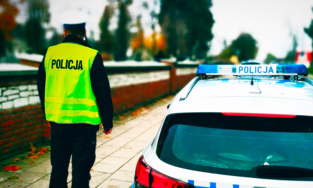 policjant stoi przy cmentarzu