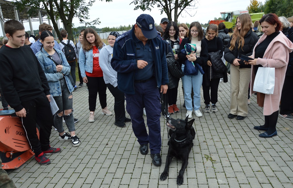 na zdjęciu widać policjanta i psa słuzbowego, wokoło stoją dzieci i młodzież
