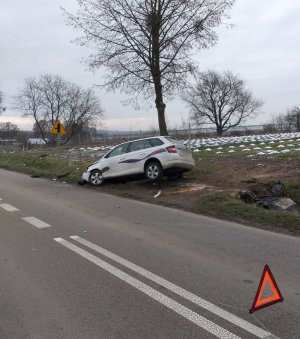 rozbity samochód marki Skoda stojący w rowie, przed nim na jezdni stoi trójkąt ostrzegawczy