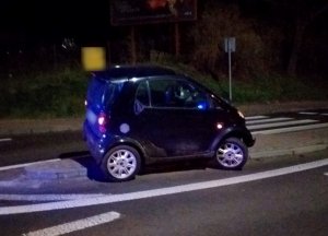 samochód marki smart stoi na środku wysepki oddzielającej pasy ruchu