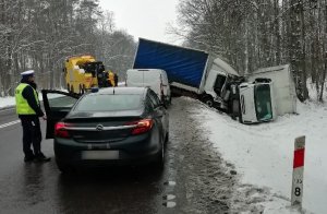 zdarzenie drogowe w Łopienniku Podleśnym, w rowie leżą dwa pojazdy dostawcze, na drodze stoi holownik oraz nieoznakowany radiowóz policji