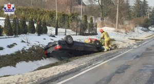 audi leży w rowie obok stoi strażak