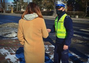 policjant wręcza kobiecie odblaski