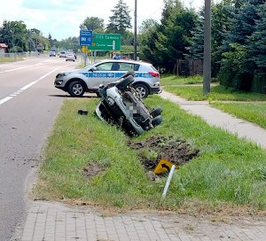 samochód dacia leżący w rowie, z anim widać radiowóz policyjny