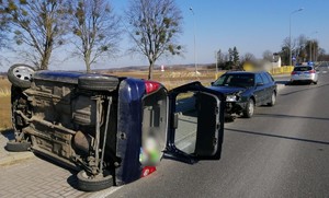 miejsce zdarzenia drogowego, na jezdni leży przewrócony samochód marki opel, zanim stoi rozbity audi