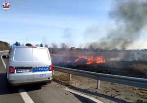 radiowóz policyjny, w tle palą się łąki