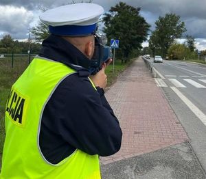 policjant drogówki mierzy prędkość pojazdów