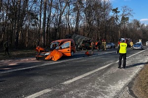 policjant na miejscu wypadku drogowego. W tle dwa samochody biorące udział wy wypadku