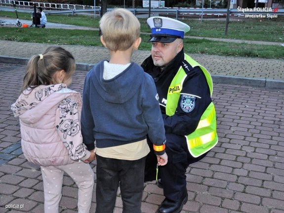 Policjant kuca przy dwójce małych dzieci.