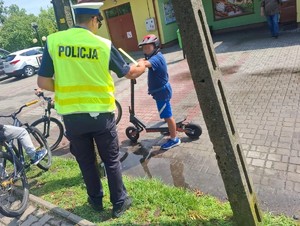 policjant ruchu drogowego wręcza odblask dziecku