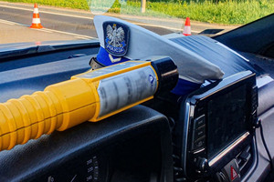 czapka policjanta ruchu drogowego i urządzenie do mierzenia alkoholu w organizmie na desce rozdzielczej radiowozu