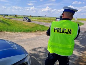 policjant ruchu drogowego mierzący prędkość przy drodze
