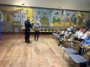 policjant z seniorką stoją przed grupą uczestników spotkania
