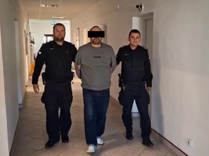 zatrzymany mężczyzna prowadzony przez dwóch policjantów