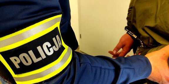 ręka policjanta z opaską z napisem Policja