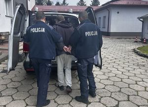 policjanci prowadzą zatrzymanego do radiowozu